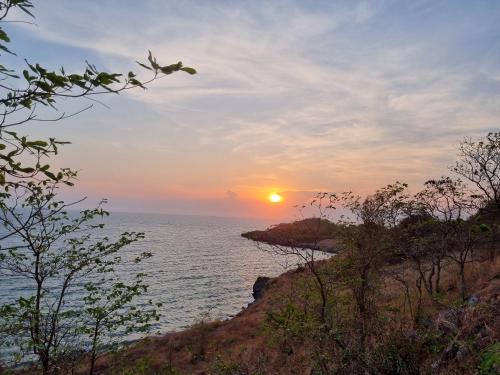a sunset over the ocean with the sun in the sky at Sawasdee Sichang Resort in Ban Tha Thewawong