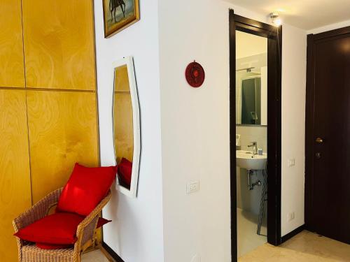 uma casa de banho com uma cadeira vermelha e um lavatório. em YouHosty - Lecco 11 em Milão