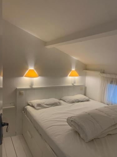 - un lit blanc avec deux lumières au-dessus dans l'établissement Maisonnette La Coti H5 avec piscine intérieure chauffée, à 400 m de la plage et ménage de fin séjour compris, à Saint-Georges-dʼOléron