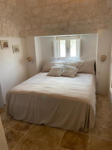 sypialnia z dużym białym łóżkiem z 2 poduszkami w obiekcie trulli mancinella w mieście Locorotondo