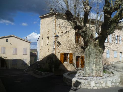 un gran edificio de piedra con un árbol delante de él en Une maison dans le village, en Ribiers