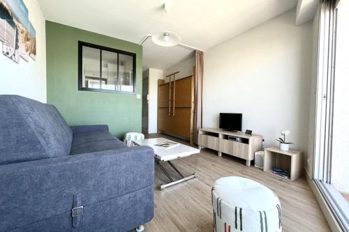 ein Wohnzimmer mit einem blauen Sofa und einem Tisch in der Unterkunft Pretty and bright studio with view on the harbor in Les Sables-dʼOlonne