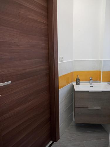a bathroom with a sink and a wooden door at colors house in Alghero