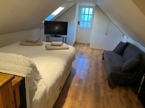 ein Schlafzimmer mit einem Bett, einem Sofa und einem TV in der Unterkunft Two Storey Annex in Cottenham