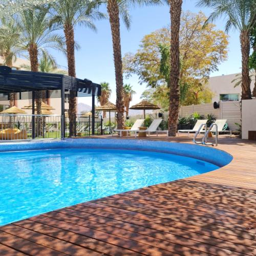 a swimming pool with palm trees in a resort at Jacob Eilat in Eilat