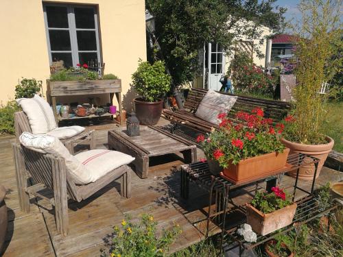 een patio met stoelen, een tafel en bloemen bij LA GUINGUETTE DE BELLEME in Bellême