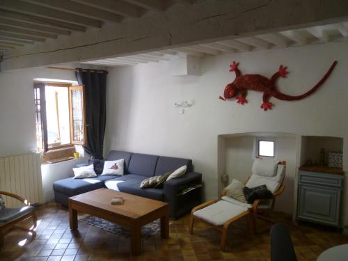 una sala de estar con un sofá azul y un dinosaurio en la pared en Une maison dans le village, en Ribiers