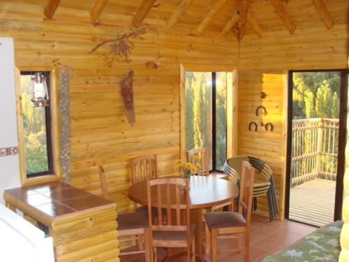 ein Esszimmer mit einem Tisch und Stühlen in einer Hütte in der Unterkunft Turismo El Recodo, cabañas y camping in San Clemente