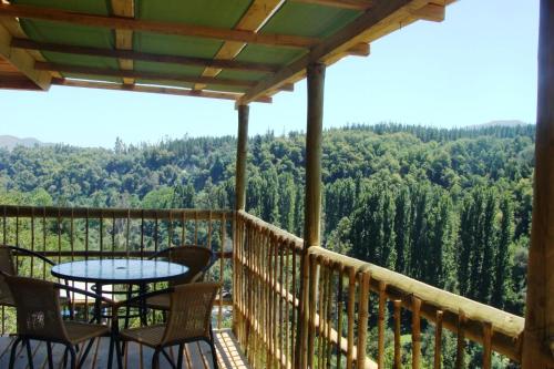 a balcony with a table and chairs and a view of trees at Turismo El Recodo, cabañas y camping in San Clemente