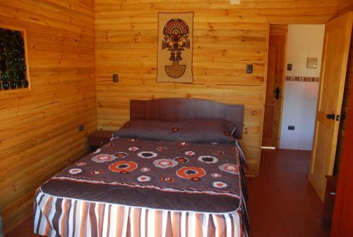 sypialnia z łóżkiem w drewnianym domku w obiekcie Turismo El Recodo, cabañas y camping w mieście San Clemente