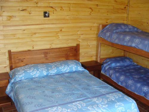 a bedroom with two beds in a log cabin at Turismo El Recodo, cabañas y camping in San Clemente