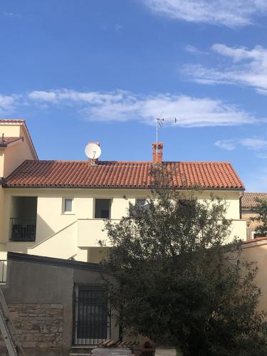 a white building with a red roof and a tree at Apartments Urban in Poreč