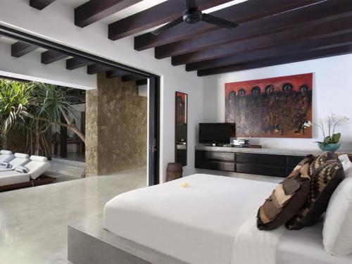 a bedroom with a white bed and a tv at Villa Hana in Canggu