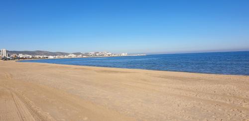 a sandy beach with the ocean and buildings in the background at Vacansis Habitaciones Privada en una Villa a un paso del Mar en Cullera in Cullera
