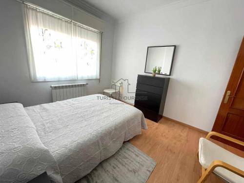 um quarto com uma cama, uma cómoda e uma janela em O cuarto de abastos em Ourense
