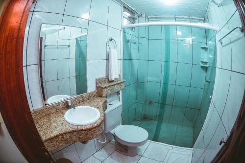 La salle de bains est pourvue de toilettes, d'un lavabo et d'un miroir. dans l'établissement Frota Palace Hotel, à Macapá