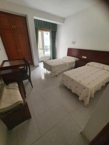 Zimmer mit 2 Betten und einem Tisch in der Unterkunft Flor de Loto in Ordes
