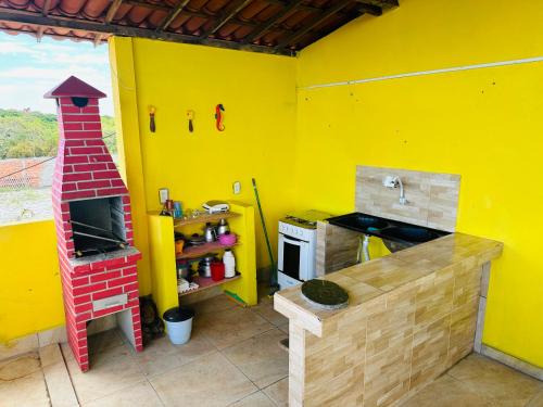 eine Küche mit einer gelben Wand mit einem Herd und einer Theke in der Unterkunft Vista Maravilhosa in Majorlândia