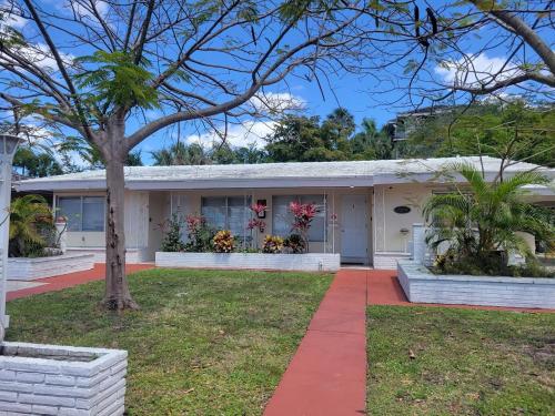 a white house with a tree in front of it at Apts with Backyard Near Fort Lauderdale Beach, Nightlife, Cruise Port, Airport in Fort Lauderdale