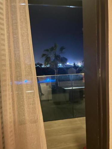 a window with a view of a palm tree at night at Anfa Place, Luxury Apartment just renovated, Ocean View in Casablanca