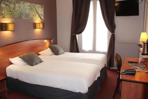 Una habitación de hotel con dos camas y un escritorio. en Kyriad Hotel XIII Italie Gobelins, en París