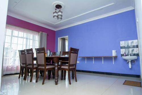 a dining room with purple walls and a table and chairs at Cherries Egul Lodges in Lilongwe