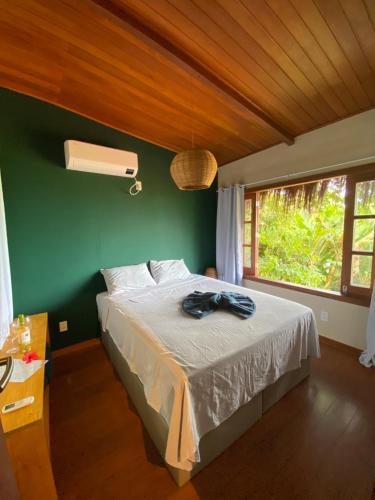 a bedroom with a bed with a green wall and a window at Saudade da Bahia in Moreré