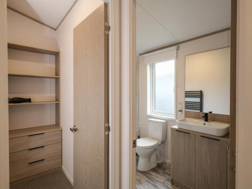 baño con aseo y lavabo y ventana en Penmarlam Lodge Retreat 18 en Fowey