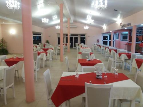 un restaurante con mesas rojas y blancas y sillas blancas en Hotel Copa Caribe en San Antonio Oeste