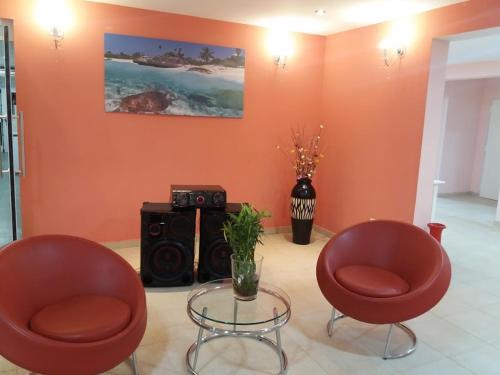 een woonkamer met 2 rode stoelen en een tafel bij Hotel Copa Caribe in San Antonio Oeste
