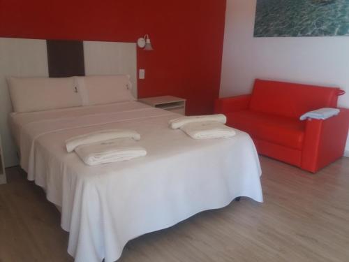 ein Schlafzimmer mit einem Bett und einem roten Sofa in der Unterkunft Hotel Copa Caribe in San Antonio Oeste
