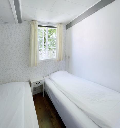two beds in a small room with a window at Pension Sandbogaard in Sandvig