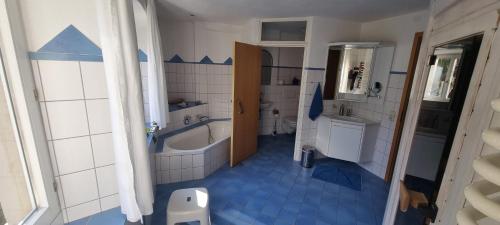 baño azul y blanco con bañera y lavamanos en Paradies 1, en Kastelhof
