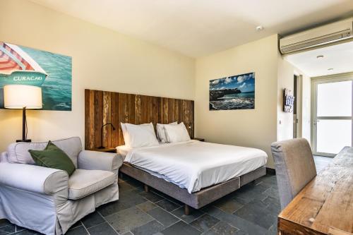 a bedroom with a bed and a couch and a chair at Bayside Boutique Hotel - Blue Bay Golf & Beach Resort in Willemstad
