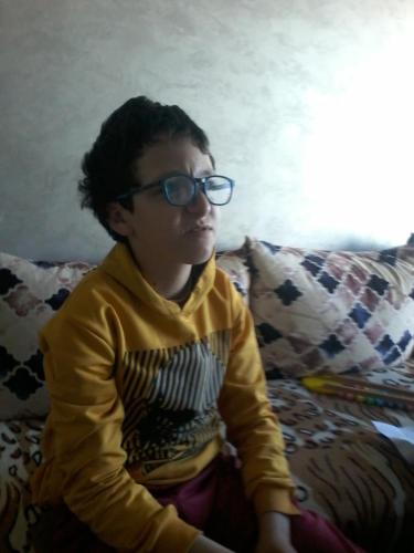 a young boy wearing glasses sitting on a couch at Chambre in Casablanca
