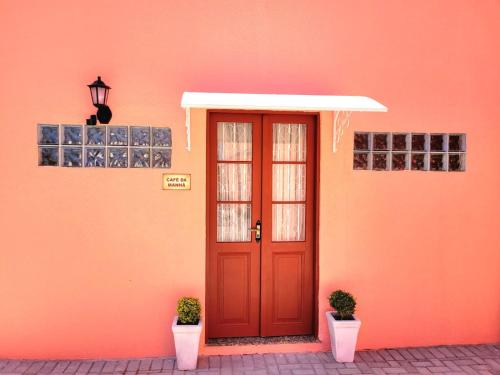 een oranje gebouw met een rode deur en twee planten bij Pousada Solar da Lapa in Lapa