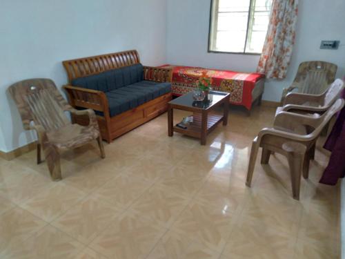 a living room with a couch and chairs and a table at Homely Home stay in Kalpetta