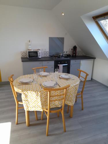 a dining room table with chairs and a kitchen at Appartements Lannion proche centre, Côtes de Granit Rose in Lannion