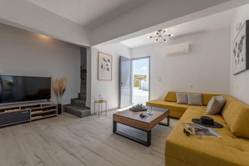 a living room with a yellow couch and a television at Casa Aelia ,Stelida Naxos in Stelida