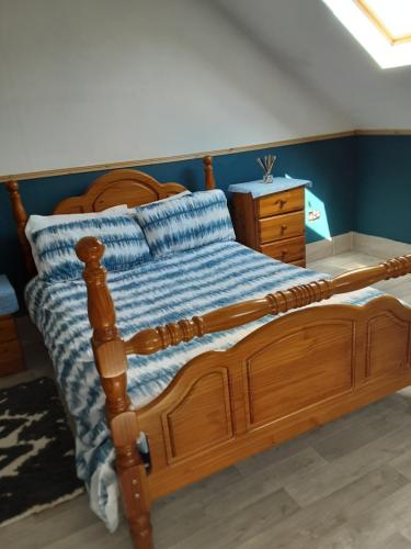 a bedroom with a wooden bed with a blue wall at Grange cottage in Edenderry
