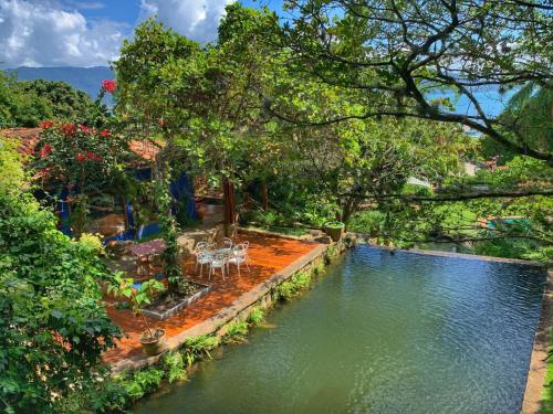 a pool of water with tables and chairs in a yard at Casas D'Água Doce - Casa Bambuzinho in Ilhabela