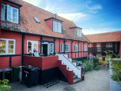 a red building with two people sitting at a counter at Pension Sandbogaard in Sandvig