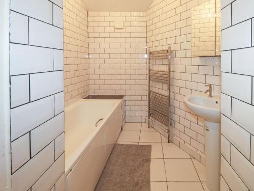 a white bathroom with a tub and a sink at 11 Magdalene Road in Torquay