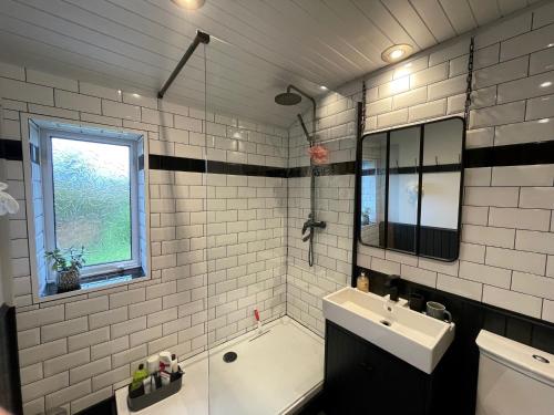 y baño con lavabo, bañera y espejo. en One bed cosy Highland cottage near Beauly, en Beauly