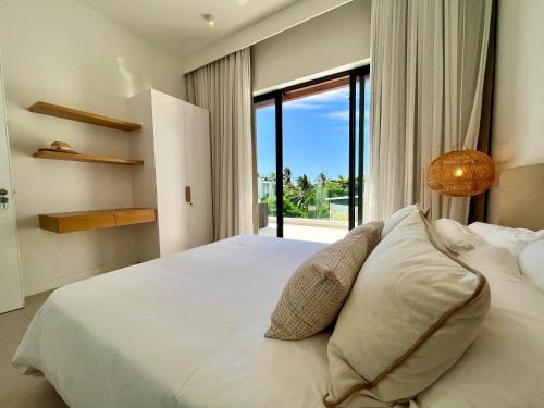 a bedroom with a white bed with a large window at Exclusive beachfront penthouse in Belle Mare