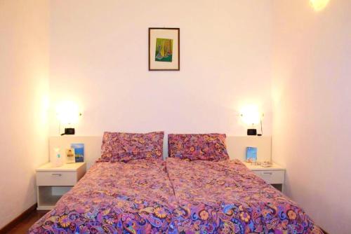 a bedroom with a bed with two tables and two lamps at Cozy apartment in Prabione, 30 m², charming balcony in Campione del Garda