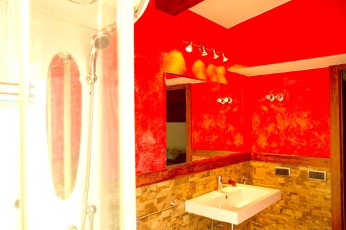 ein rotes Badezimmer mit einem Waschbecken und einem Spiegel in der Unterkunft 10 bedrooms villa with private pool jacuzzi and enclosed garden at Sils in Sils
