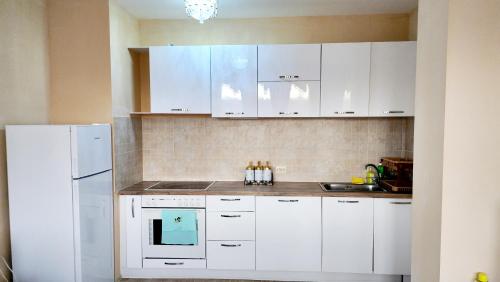una cucina con armadietti bianchi e frigorifero bianco di Paradise a Nikolajevka