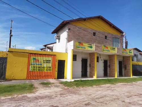 un edificio giallo e bianco sul lato di una strada di Temporada no Atalaia a Salinópolis