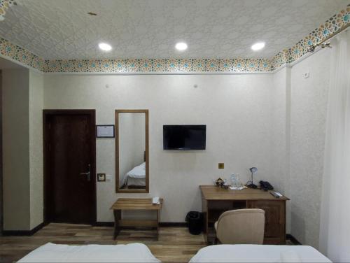 Habitación con 2 camas, espejo y mesa. en Ayvan Plaza hotel, en Bukhara